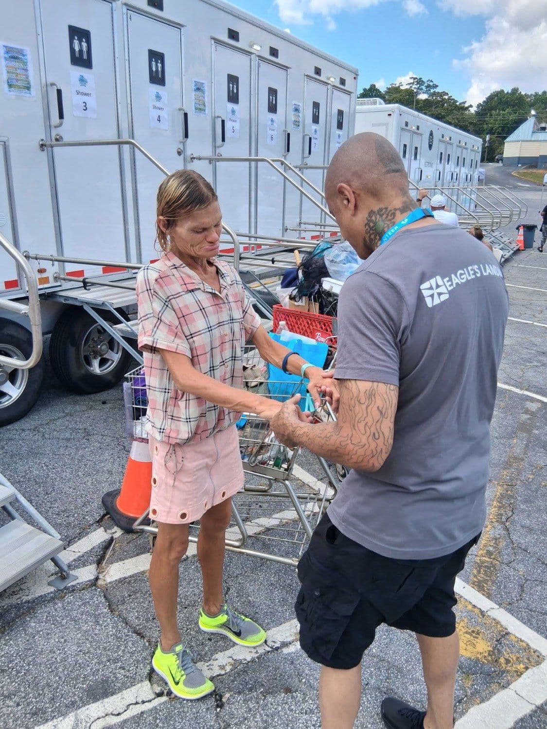 A Fresh Hope volunteer greets a guest beside the shower trailer, taking her hand.