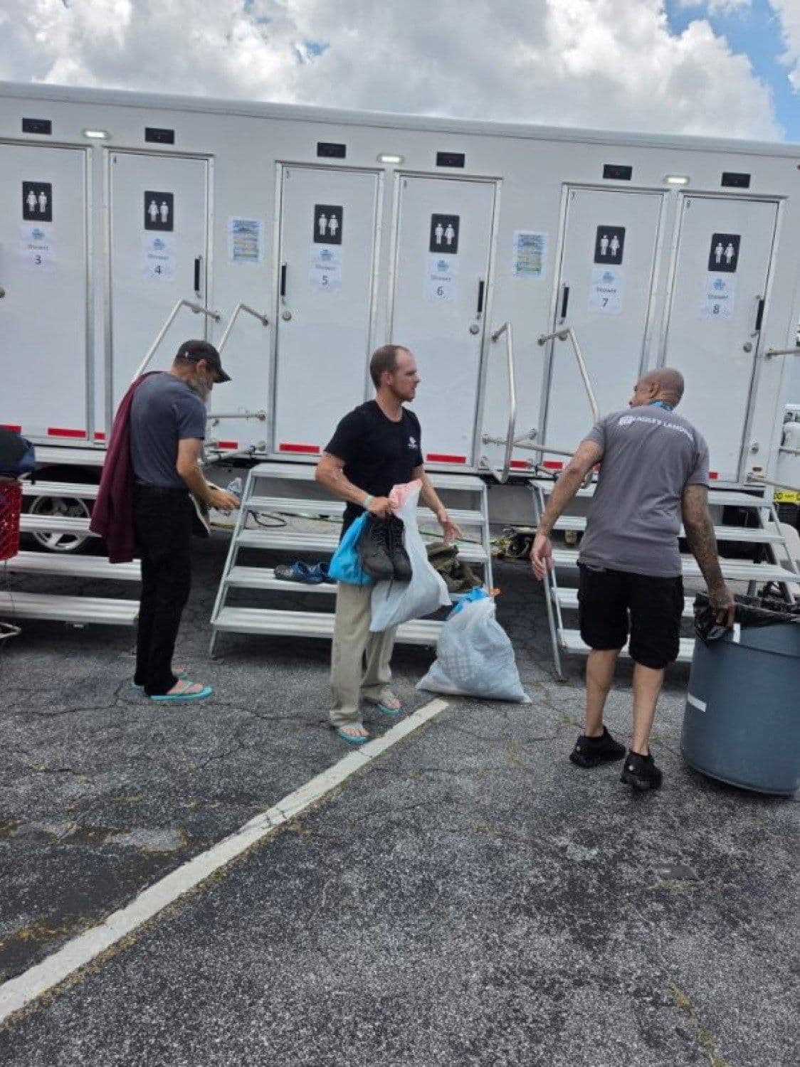 Guests carrying bags of laundry toward the trailer on a Fresh Hope service day.