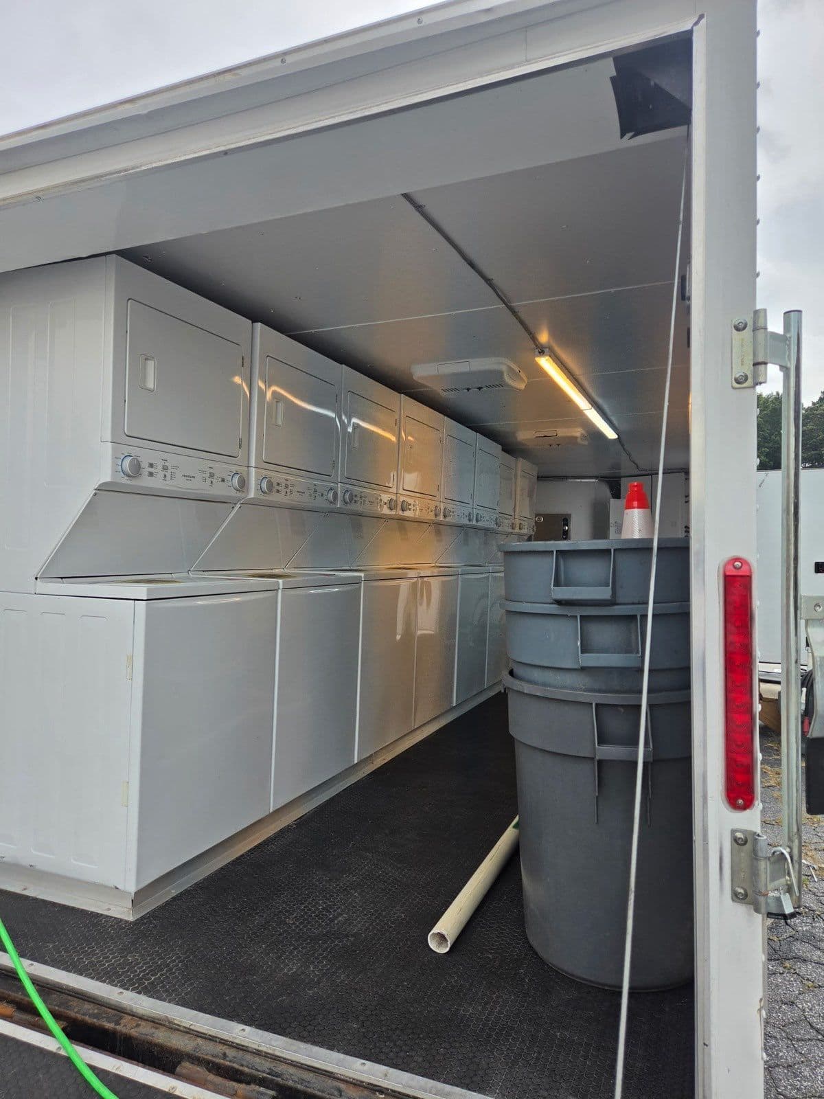 Inside the laundry trailer: a row of stacked washers and dryers ready for a service day.