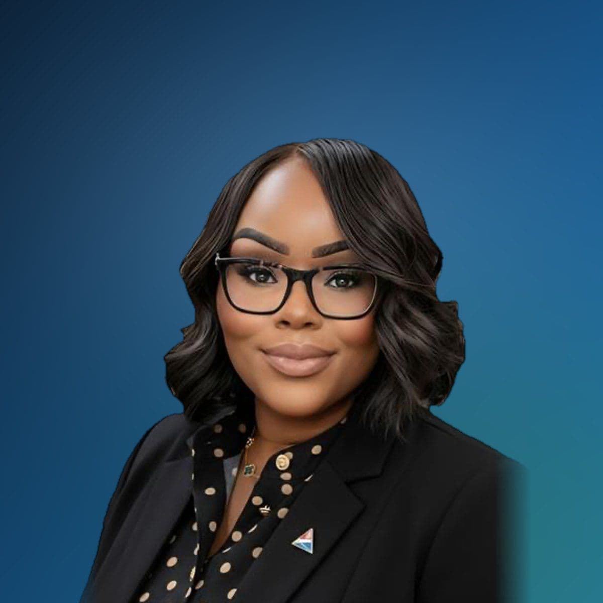 Brandi R. Cousin Sims, smiling, in glasses, a black blazer and a polka-dot blouse.