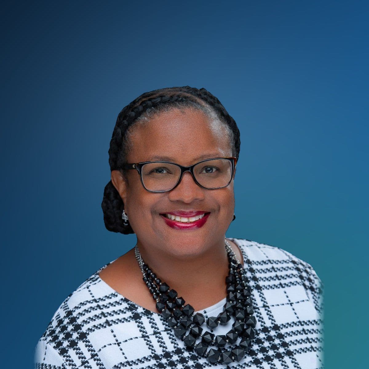 Kira Harris-Braggs, smiling, in glasses and a black and white checked top.