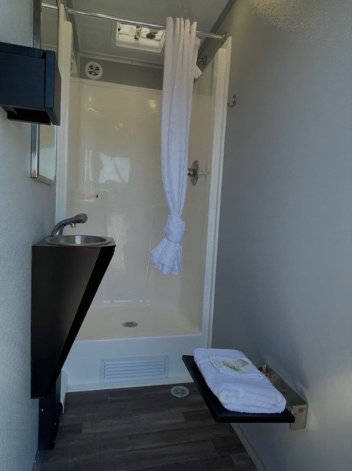 A private shower stall with a folded towel and fresh soap set out on the shelf.
