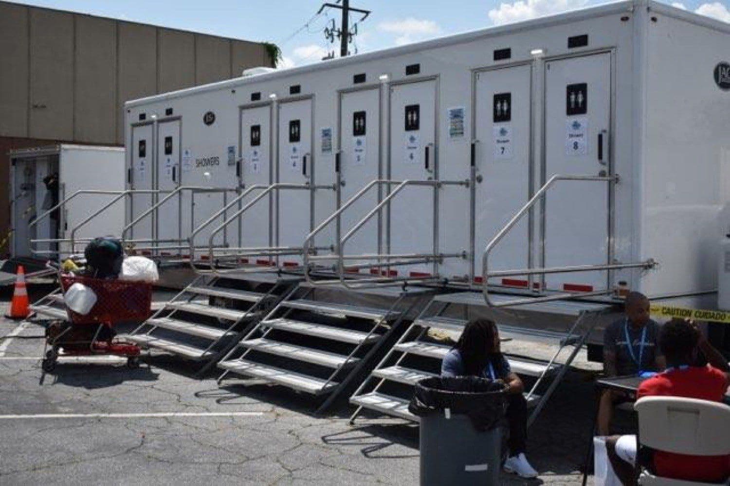 Guests and volunteers at a Fresh Hope service day, with the shower trailer and an intake table set up in the lot.